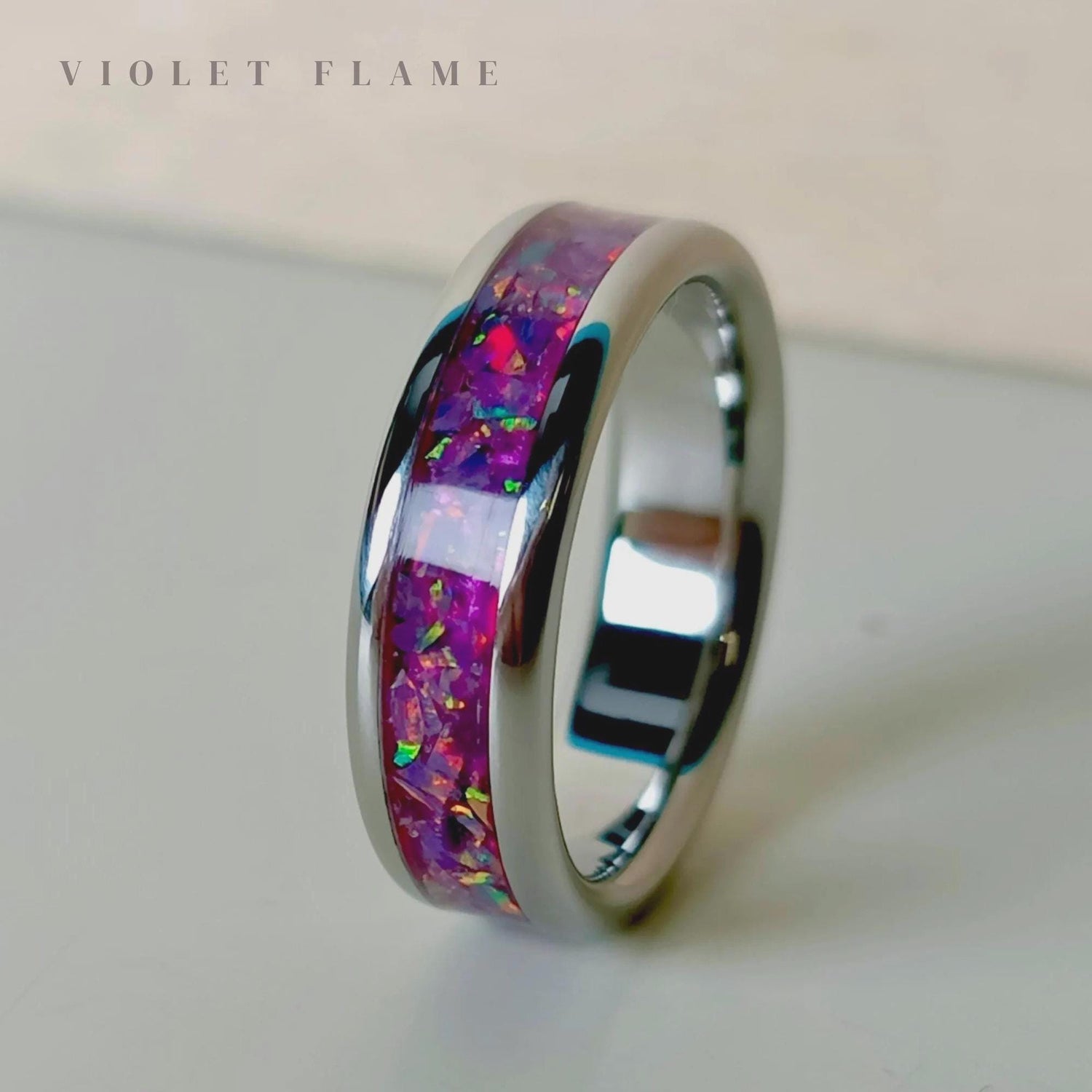Ring with colorful inlay on a light background, branded 'Violet Flame'.